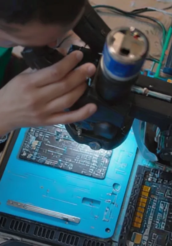 Técnico soldando componentes en una placa bajo microscopio