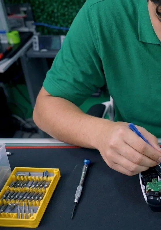 Reparador con playera verde usando un desarmador de precisión