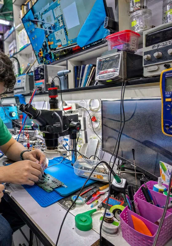Banco de trabajo con microscopio, multímetro y equipo en reparación